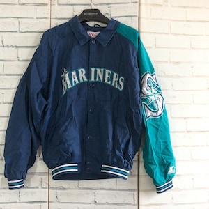 May include: A blue and green baseball jacket with the word "Mariners" in white lettering on the front. The jacket has a snap closure and a green and white star design on the right sleeve.