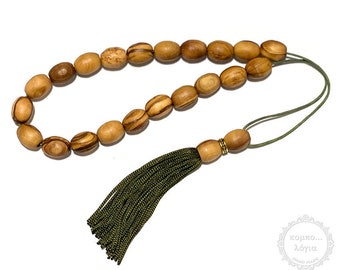Puede incluir: Un collar de cuentas de oración de madera con un borla verde. Las cuentas están hechas de madera de olivo y tienen un patrón de veta de madera natural. La borla está hecha de una tela verde suave.