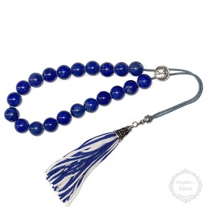 May include: A blue lapis lazuli prayer bead mala with a silver tassel and a silver clasp. The mala has a blue and white tassel.