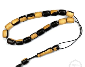 Puede incluir: Un collar de cuentas de oración de madera con cuentas negras y marrones. Las cuentas son cilíndricas y tienen un acabado liso. El collar tiene un borla al final.