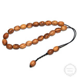 Puede incluir: Un collar de cuentas de madera ovaladas en tonos marrones, ensartadas en un cordón negro. Las cuentas tienen un patrón de vetas de madera natural. El cordón termina en una borla de tres cuentas y una sola cuenta.