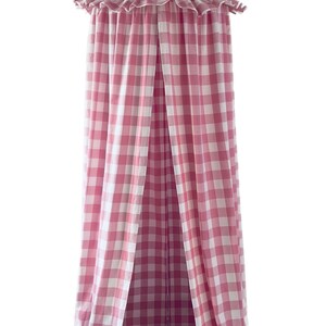May include: Pink and white gingham canopy for a bed. The canopy has a ruffled edge and hangs from a single point.
