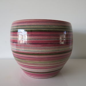 Könnte beinhalten: Ein großer, runder Keramiktopf mit einem gestreiften Muster in den Farben Rosa, Grün und Weiß.
