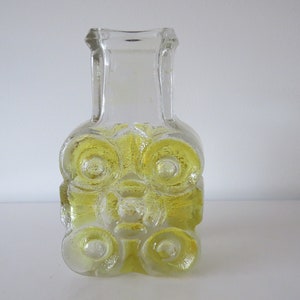 Peut inclure: Un vase en verre transparent avec une teinte jaune et un design texturé. Le vase a une large ouverture et un col étroit.