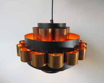May include: A black and copper mid-century modern pendant light fixture with a circular design. The light fixture has multiple layers of copper shades.