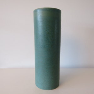Puede incluir: Un jarrón cilíndrico alto de cerámica con un esmalte verde azulado liso.