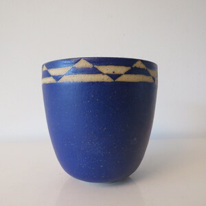 May include: A blue ceramic cup with a white geometric pattern around the rim.