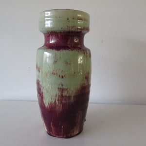 May include: A ceramic vase with a green and burgundy glaze. The vase has a rounded body and a wide mouth.