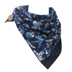 Può includere: Una sciarpa bandana blu navy con chiusura a bottone. La sciarpa presenta un motivo ripetuto di gru origami e disegni floreali in blu e oro. La sciarpa è realizzata in un tessuto morbido.