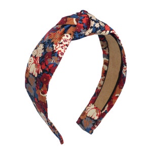 Op de afbeelding: Een geknoopt hoofdband met een bloemenpatroon in rood, blauw en wit.