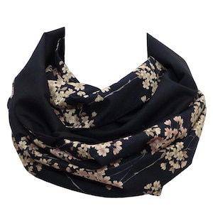 Könnte beinhalten: Ein schwarzer Schal mit einem Blumenmuster. Die Blumen sind hellrosa und cremefarben und in einem sich wiederholenden Muster angeordnet. Der Schal ist aus einem weichen, leichten Stoff.