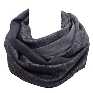 Pode incluir: Uma echarpe cinza escura com uma borda azul denim contrastante. A echarpe é feita de um tecido macio e texturizado e é perfeita para adicionar um toque de calor e estilo a qualquer roupa.