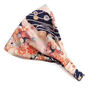 May include: A wide headband with a floral pattern in shades of pink, orange, and navy blue. The fabric features a Japanese-inspired design with flowers and wave-like patterns. The headband is made of soft fabric and is designed to be worn around the head.