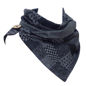 Peut inclure: Une écharpe à motifs noirs et gris avec un bouton en bois. L'écharpe est faite d'un tissu doux et confortable et présente un motif géométrique.