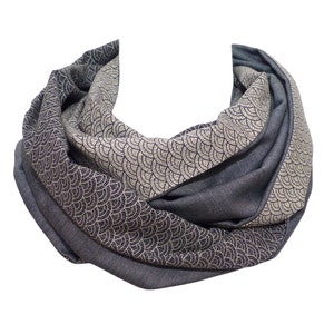 Könnte beinhalten: Ein grauer und goldfarbener Schal mit geometrischem Muster. Der Schal ist gefaltet und zu einem Kreis gerollt.