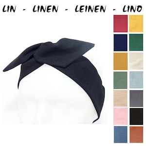 Può includere: Fascia per capelli in lino nero con un fiocco. La fascia è mostrata su uno sfondo bianco. L'immagine include anche una cartella colori con 12 colori diversi di lino.