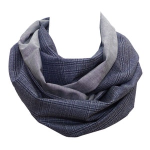 Könnte beinhalten: Ein marineblauer und grauer Loop-Schal. Der Schal ist aus einem weichen Stoff gefertigt und hat ein Karomuster in Marineblau und eine einfarbige graue Farbe. Der Schal ist so konzipiert, dass er um den Hals geschlungen getragen wird.