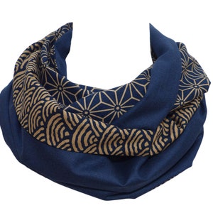 Könnte beinhalten: Ein blauer und goldfarbener Infinity-Schal mit Muster. Der Schal ist aus weichem, bequemem Stoff und hat ein geometrisches Design.