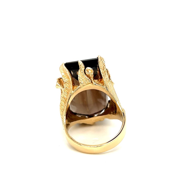 May include: A gold ring with a large, dark brown gemstone set in a detailed, ornate design.