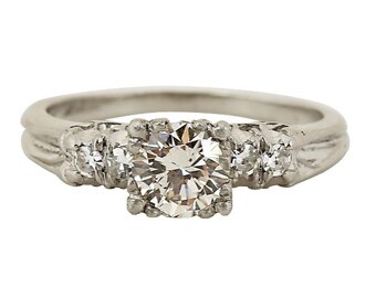 May include: A silver engagement ring with a large round diamond in the center and smaller diamonds on either side.