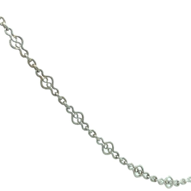 Op de afbeelding: Een zilveren ketting met een delicaat, ingewikkeld ontwerp. Elke schakel is in de vorm van een acht.