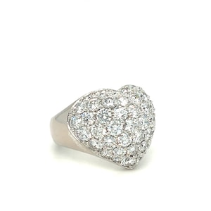 May include: A silver ring with a heart-shaped top covered in small, clear diamonds.