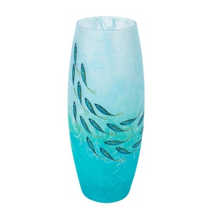 May include: A cylindrical glass vase featuring a gradient colour scheme that transitions from light sky blue at the top to a vibrant turquoise at the base. The surface is decorated with a school of small, dark blue fish with gold accents.