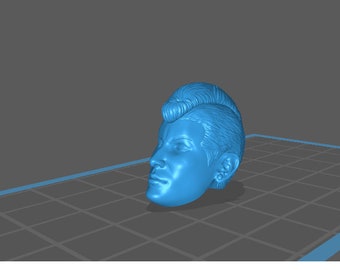 Puede incluir: Una figurita de cabeza de persona impresa en 3D de color azul con un peinado mohicano. La figurita está mirando hacia la derecha y tiene un ojo cerrado.