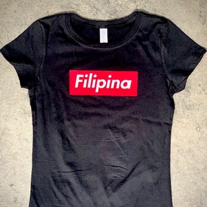 Op de afbeelding: Zwart T-shirt met een rode doos met daarop "Filipina".