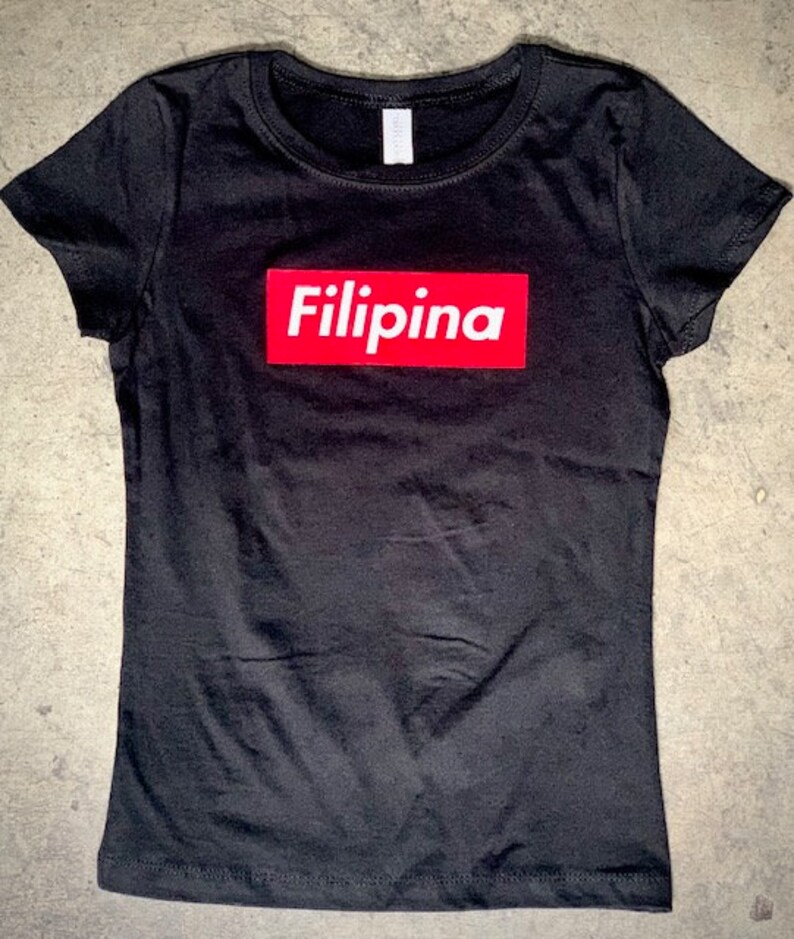 Op de afbeelding: Zwart T-shirt met een rode doos met daarop "Filipina".