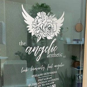 May include: A white sign with a stylised floral design and wings, with the text "the angelic aesthetic LLC" and the tagline "look heavenly, feel angelic". Below the tagline is the text "eyelash extensions", "Instagram @_THEANGELICAESTHETIC", and "scan to follow".