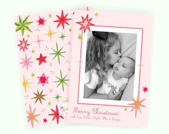May include: A light pink holiday greeting card featuring a pattern of red, green, and yellow stars. The card includes a black and white photograph of two children and the text Merry Christmas with love, Daryn, Wyath, Ella, & Sawyer.