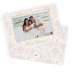 May include: A Christmas card featuring a family photo within a gold-bordered frame. The card has a light pink background with a repeating pattern of floral and whimsical illustrations. The text "Merry Christmas!" is displayed.