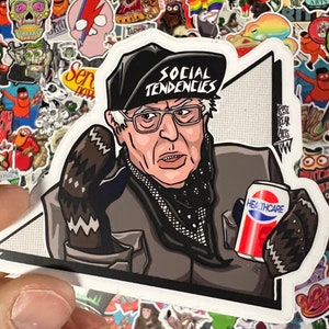 May include: A sticker featuring a cartoon illustration of a man wearing a black hat with the words "SOCIAL TENDENCIES" on it. He is holding a can of soda with the word "HEALTHCARE" on it. The sticker is on a white background.