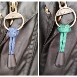 May include: Two Barbour brand zipper pulls with a metal ring and a knotted rope. The rope on the left is blue and the rope on the right is green.