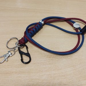 May include: A blue and burgundy paracord lanyard with a silver metal clasp and a black swivel clip.