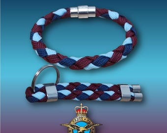 May include: A braided bracelet and keychain in blue, navy, and maroon colors with silver metal accents. The keychain has a key ring. The bracelet has a magnetic clasp. The image also includes the Royal Air Force emblem.