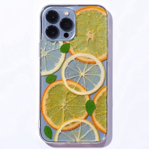 Clear resin phone case with lemon and orange slices, leaves is on the sierra blue iphone 13 pro max.