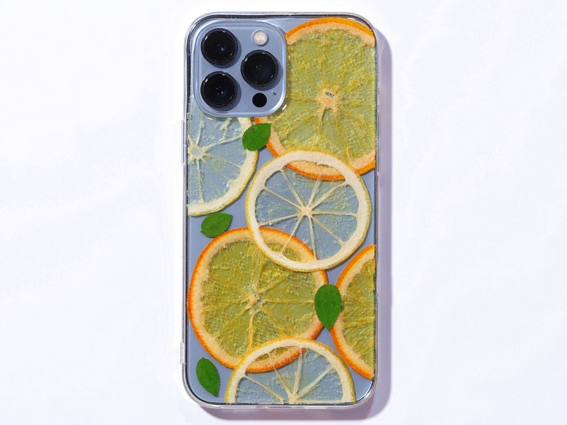 Clear resin phone case with lemon and orange slices, leaves is on the sierra blue iphone 13 pro max.