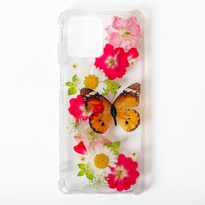 May include: A clear phone case with a pressed flower and butterfly design. The case features pink, white, and orange flowers, and a brown and orange butterfly.