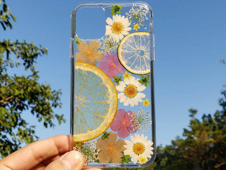 Handcrafted transparent phone case with pressed citrus slices and wildflowers on a clear background, ideal for those seeking a unique, nature-inspired accessory for their device.