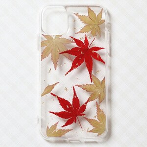 May include: A clear smartphone case featuring an embedded design of pressed maple leaves in vibrant shades of red and pale yellow, accented with small flecks of gold foil scattered throughout the transparent surface of the protective cover.