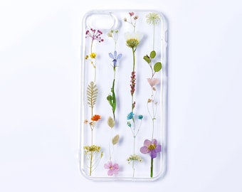 May include: A clear, rectangular phone case featuring an arrangement of various pressed, dried flowers in shades of yellow, blue, purple, pink, and green. The floral design is vertically oriented, showcasing delicate stems, leaves, and petals.