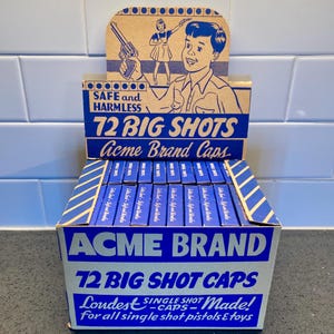 May include: A vintage Acme Brand 72 Big Shot Caps display box. The box is blue and white with text and illustrations. The box reads "Safe and Harmless" and "Loudest Single Shot - Made!" for single shot pistols & toys.