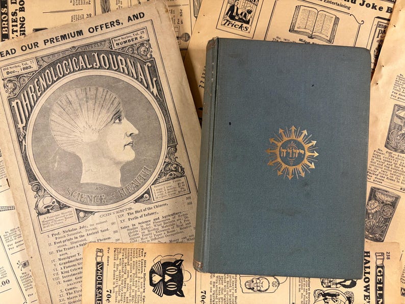 Puede incluir: Un libro antiguo de color verde azulado con un emblema dorado y un peri&oacute;dico vintage. El peri&oacute;dico se titula "Phrenological Journal" y presenta una ilustraci&oacute;n de perfil. El fondo est&aacute; lleno de recortes de peri&oacute;dicos antiguos.