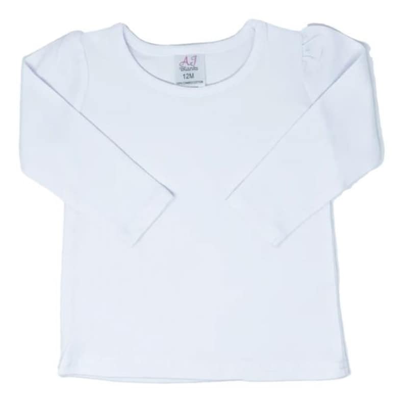 May include: White long-sleeve shirt with a round neckline. The shirt has a small tag with the text "AJ Blanks 12M 100% Combed Cotton" on the front.