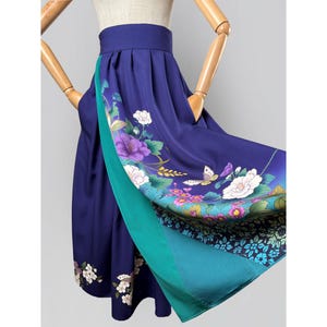 May include: A flowing, knee-length skirt in deep blue with a floral print. The skirt features a teal panel that adds a pop of color. The floral design includes white and purple flowers, and butterflies.
