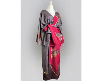 Può includere: Un kimono grigio e rosso con un motivo floreale. Il kimono è legato in vita con una cintura.