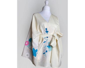 May include: A cream-colored kimono with a floral print in shades of blue, pink, and white. The kimono has a wrap-around style and a tie belt.