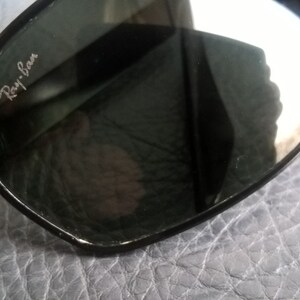 May include: Black Ray-Ban sunglasses with a textured frame and dark lenses.
